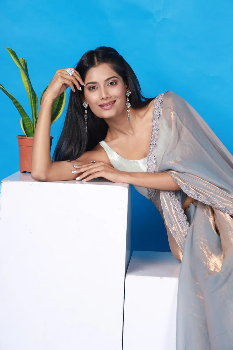 Snehal Patil in a grey saree against a blue backdrop