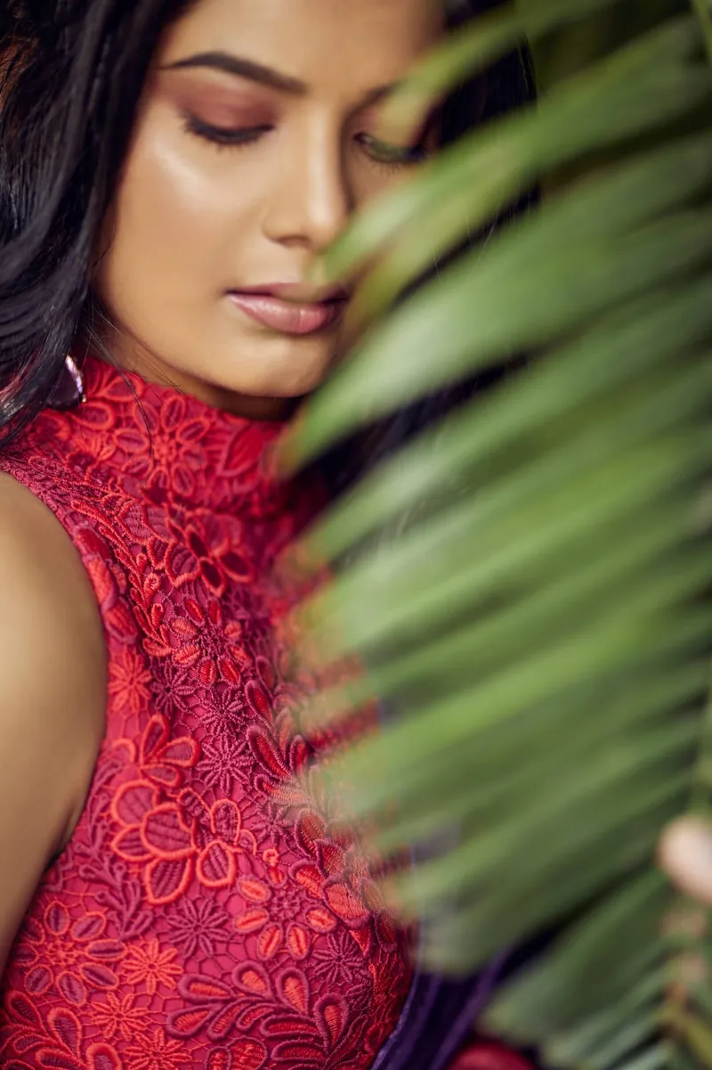 Snehal Patil in a red lace top, partly behind a palm leaf